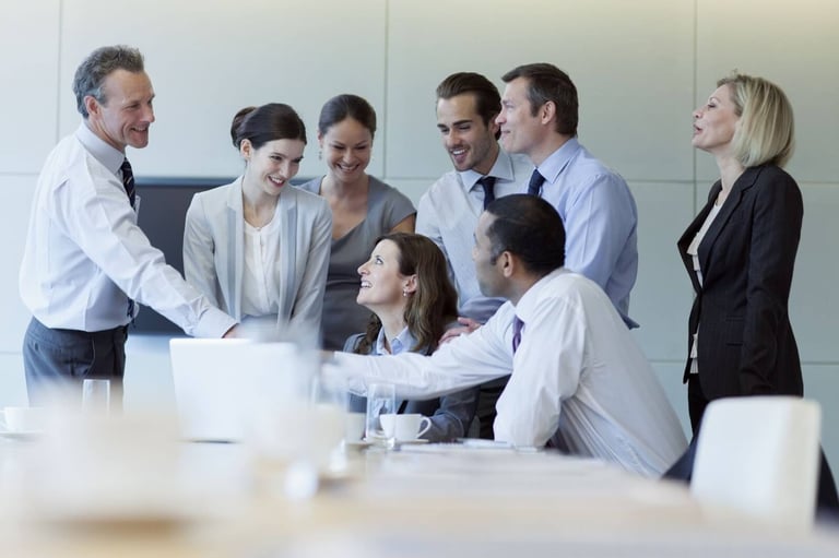 Imagem de uma equipe de negócios B2B conversando em uma sala de reunião, todos estão com roupas sociais brancas e pretas, e estão sorrindo, como se comemorassem algo