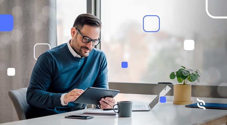 foto de um homem de barba e óculos segurando um tablet e em frente a um notebook entendendo o Billing e como automatizar o faturamento