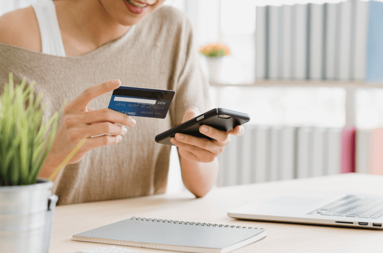  empreendedora sorrindo com cartão e celular na mão descobrindo como fazer intermediação de pagamentos online