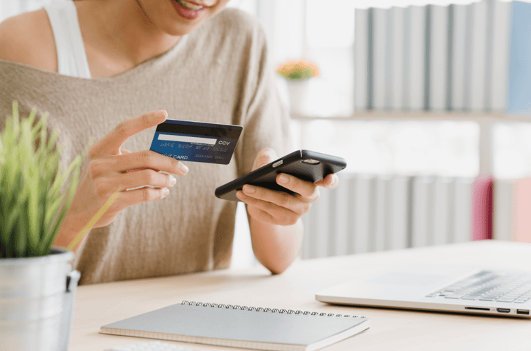 empreendedora sorrindo com cartão e celular na mão descobrindo como fazer intermediação de pagamentos online