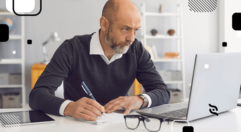 homem idoso em frente ao notebook com papel e caneta praticando lifelong learning
